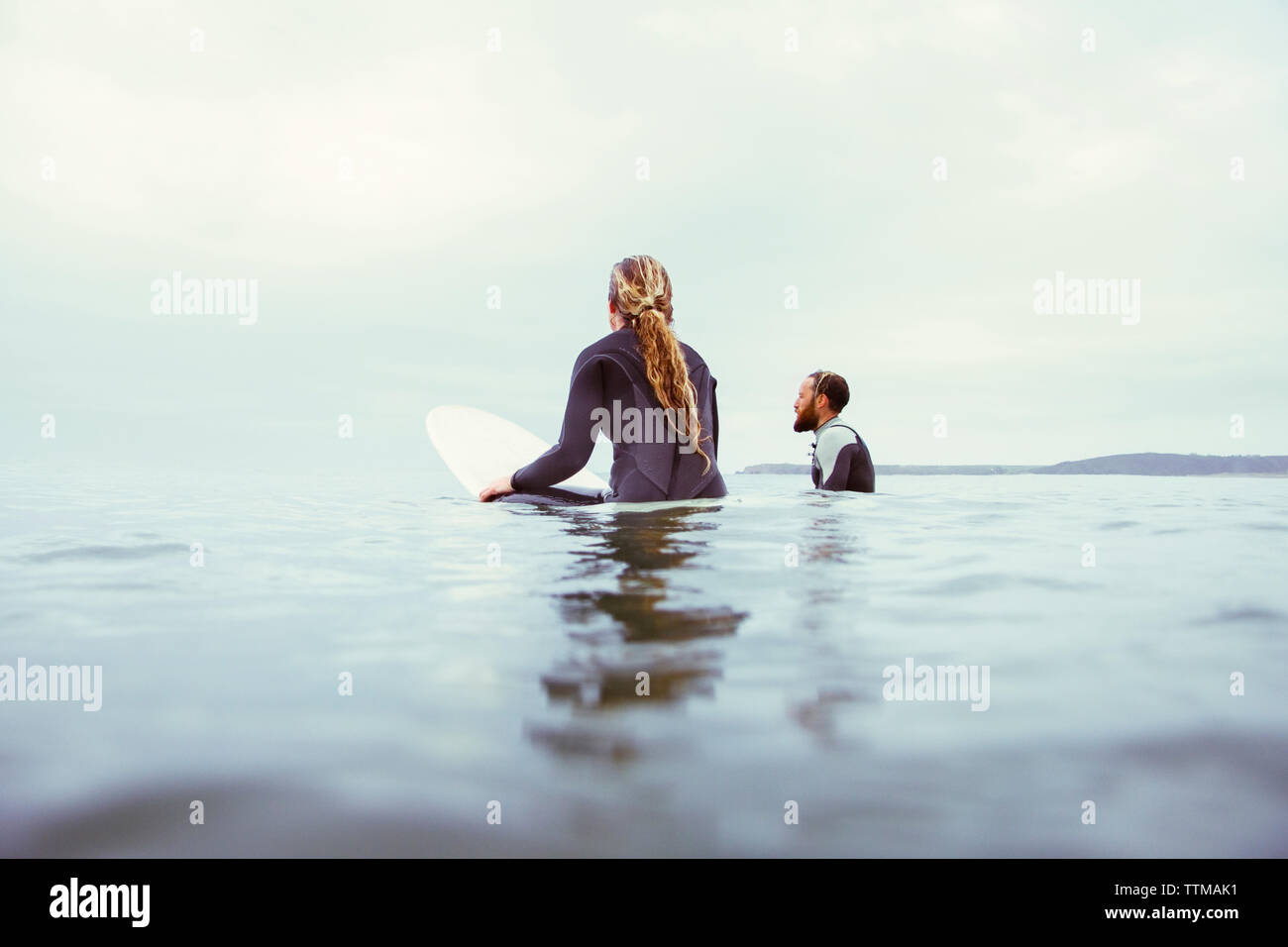 Surfers mâles et femelles en relaxant contre la mer ciel nuageux Banque D'Images