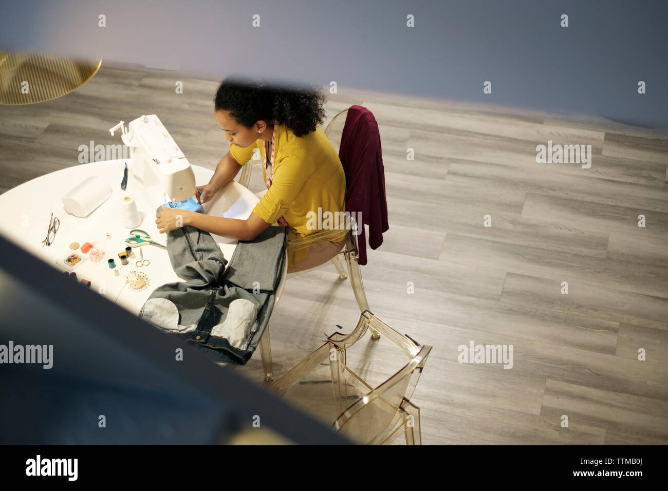 Portrait de femme entrepreneur jeans couture avec machine à coudre sur la table in office Banque D'Images