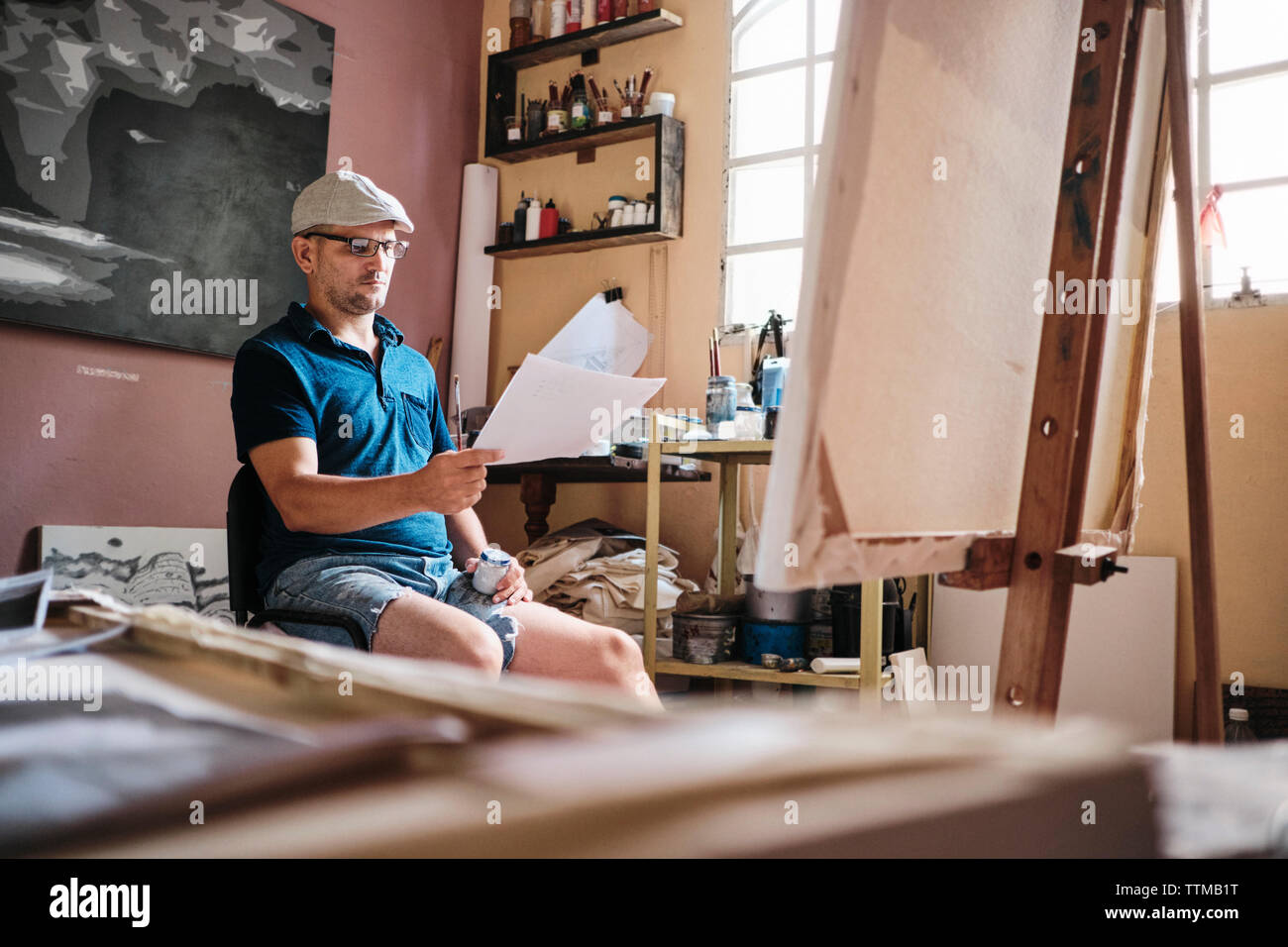 L'homme travaillant comme peintre à la recherche à l'image de référence pour la nouvelle peinture Banque D'Images