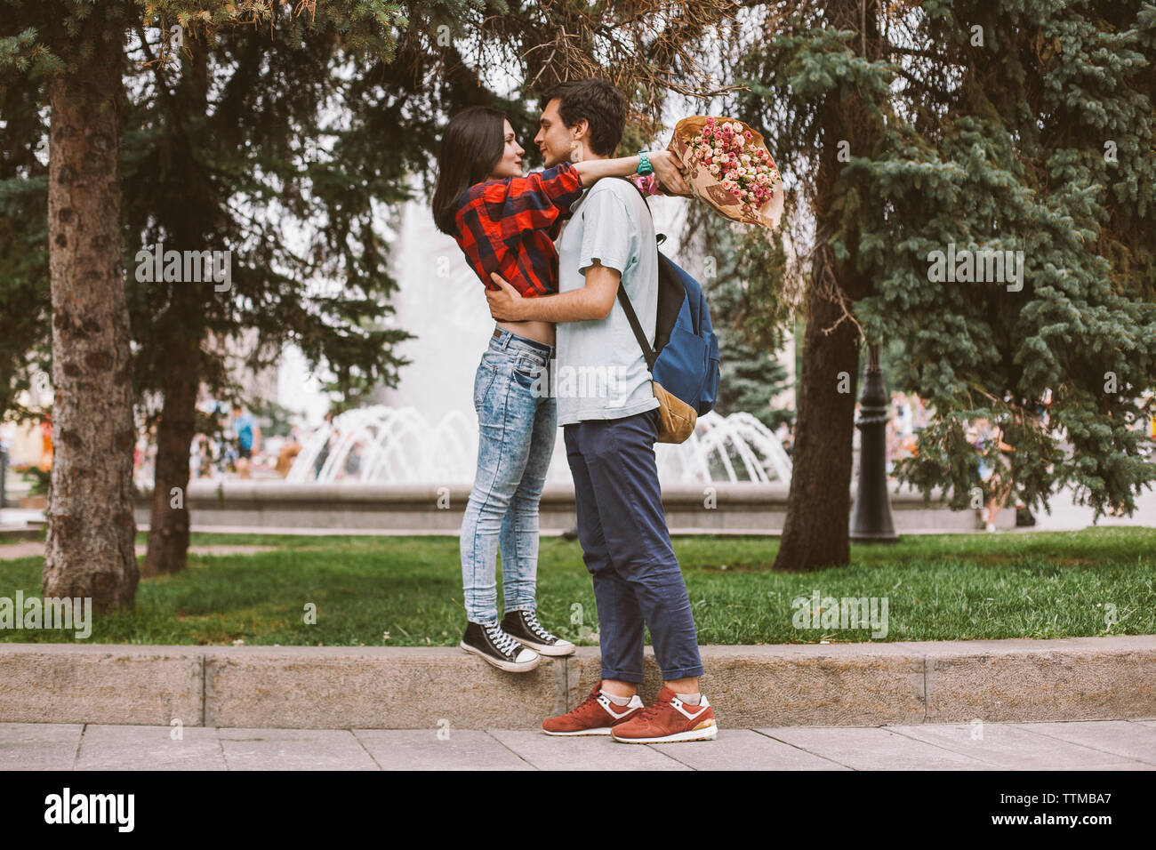 Toute la longueur du jeune couple romancing sur sentier contre des arbres en ville Banque D'Images