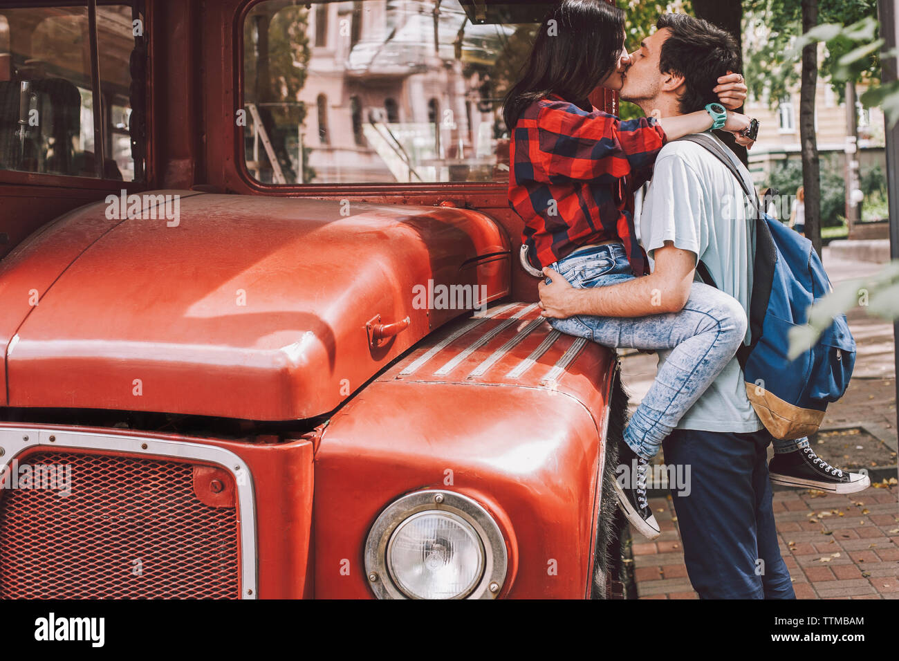 Vue latérale du jeune couple s'embrasser sur la bouche en ville par bus d'époque Banque D'Images