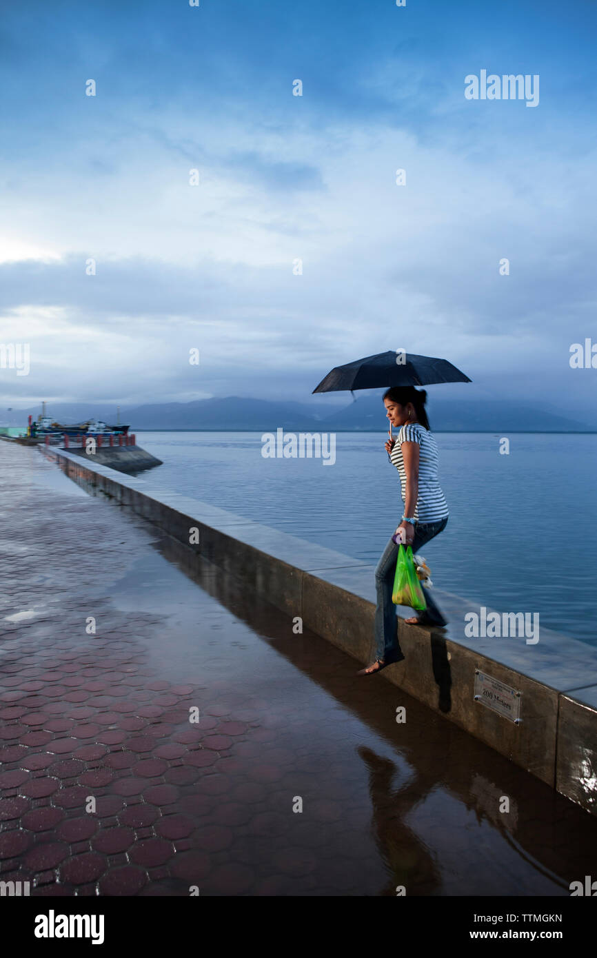 PHILIPPINES, Palawan, Puerto Princesa, femme pas de fo la mer mur dans la zone portuaire de la ville Banque D'Images