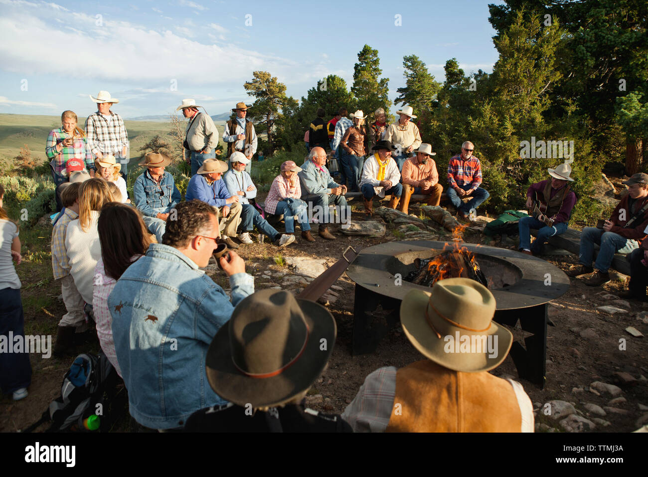 USA, Wyoming, du cantonnement, réduite à un ranch s'asseoir autour d'un feu de camp et d'écouter un homme jouer de la guitare et chanter des chansons country western, Abara Ranch Banque D'Images