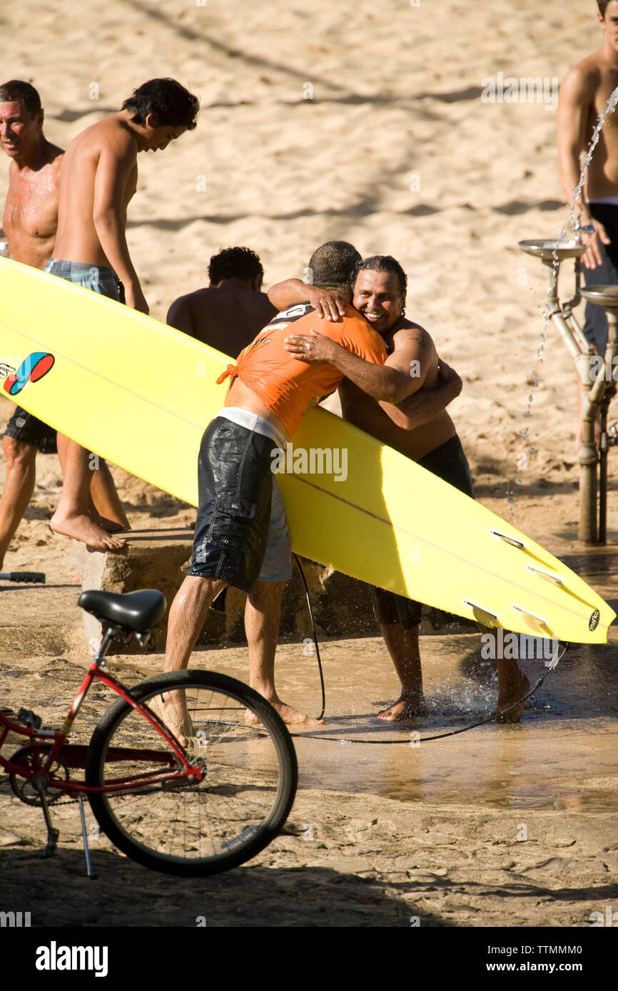 USA, Hawaii, Oahu, embrassant les surfeurs sur la plage, Waimea Bay Banque D'Images