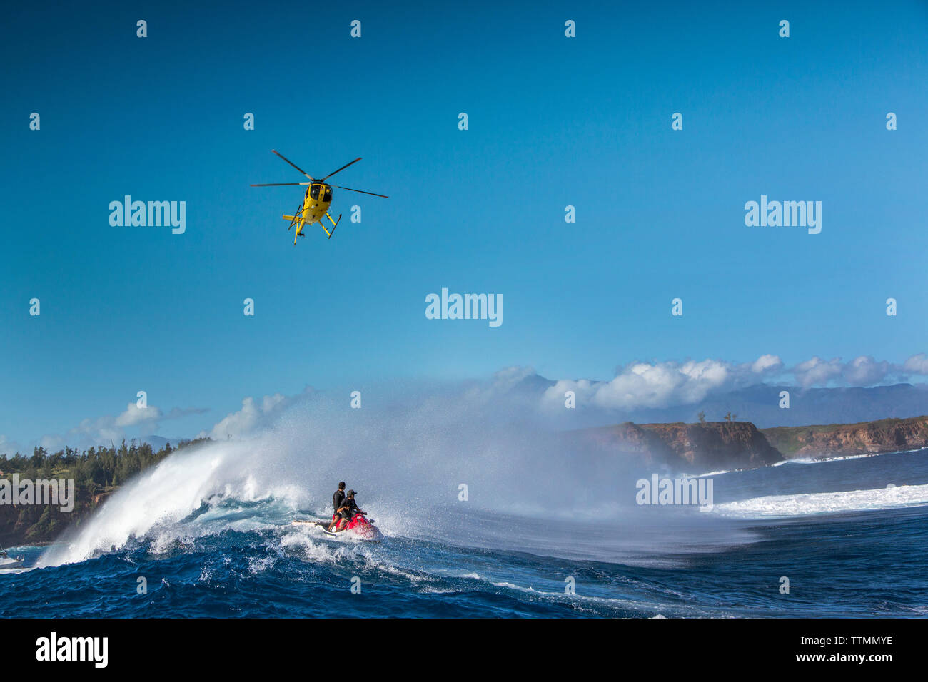 USA, Hawaii, Maui, Jaws, un hélicoptère survolant les grosses vagues et surfeurs de Peahi sur le Northshore Banque D'Images