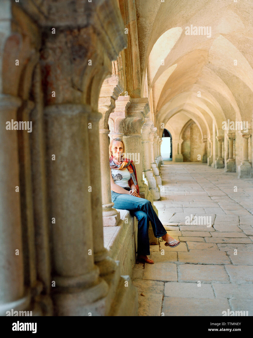 FRANCE, Bourgogne, jeune femme assise à l'Abbaye de Fontenay, Marmagne Banque D'Images