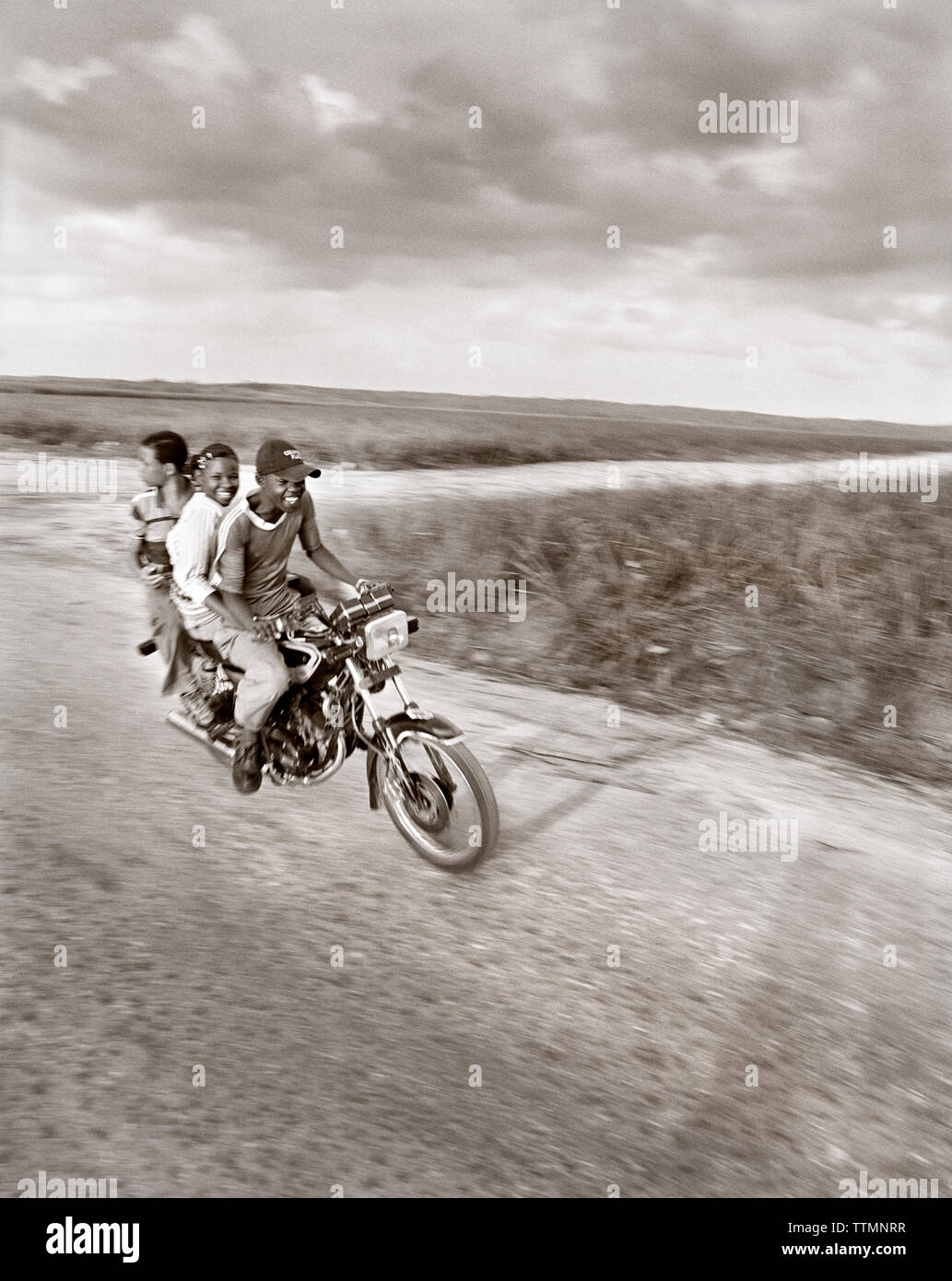 République dominicaine, trois amis appréciant un tour de moto sur une route rurale près de Casa de Campo (B&W) Banque D'Images