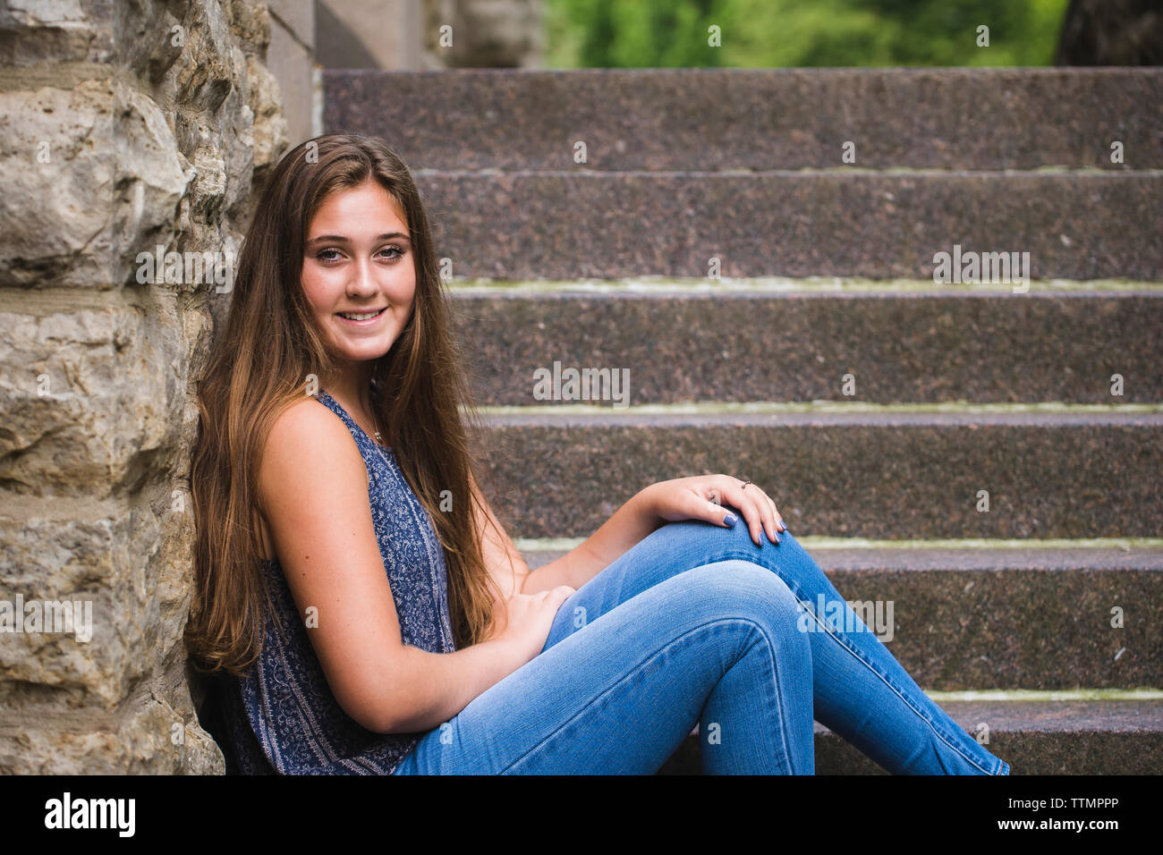 Portrait of smiling woman with long hair sitting on steps Banque D'Images