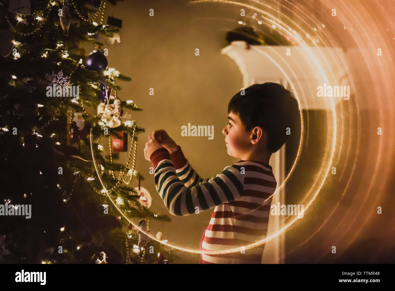 Close up of a young boy decorating a Christmas Tree dans la nuit. Banque D'Images