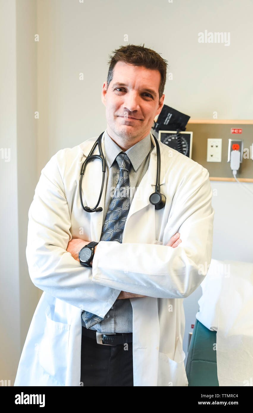 Un médecin en blouse blanche debout à côté d'une table d'examen dans un hôpital. Banque D'Images