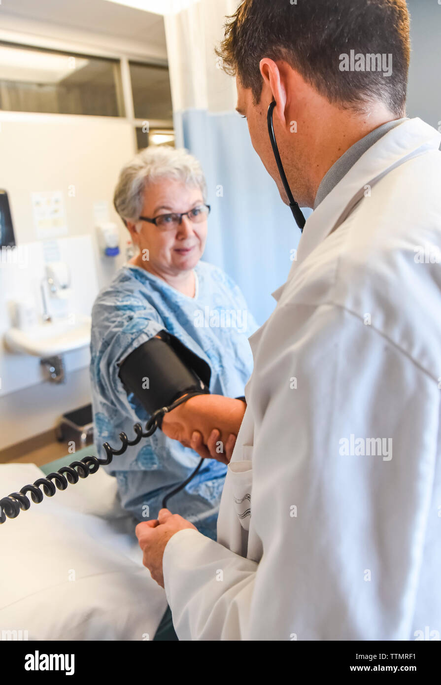 Médecin de prendre la tension artérielle d'un patient plus âgé en milieu clinique. Banque D'Images