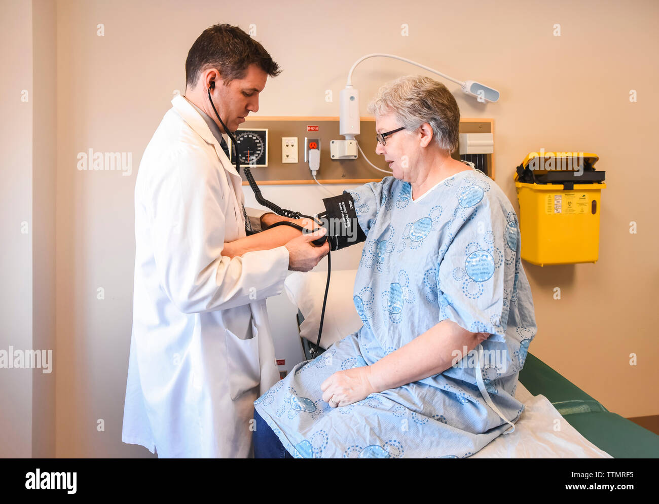 Médecin de prendre la tension artérielle du patient plus âgé portant une blouse en clinique. Banque D'Images