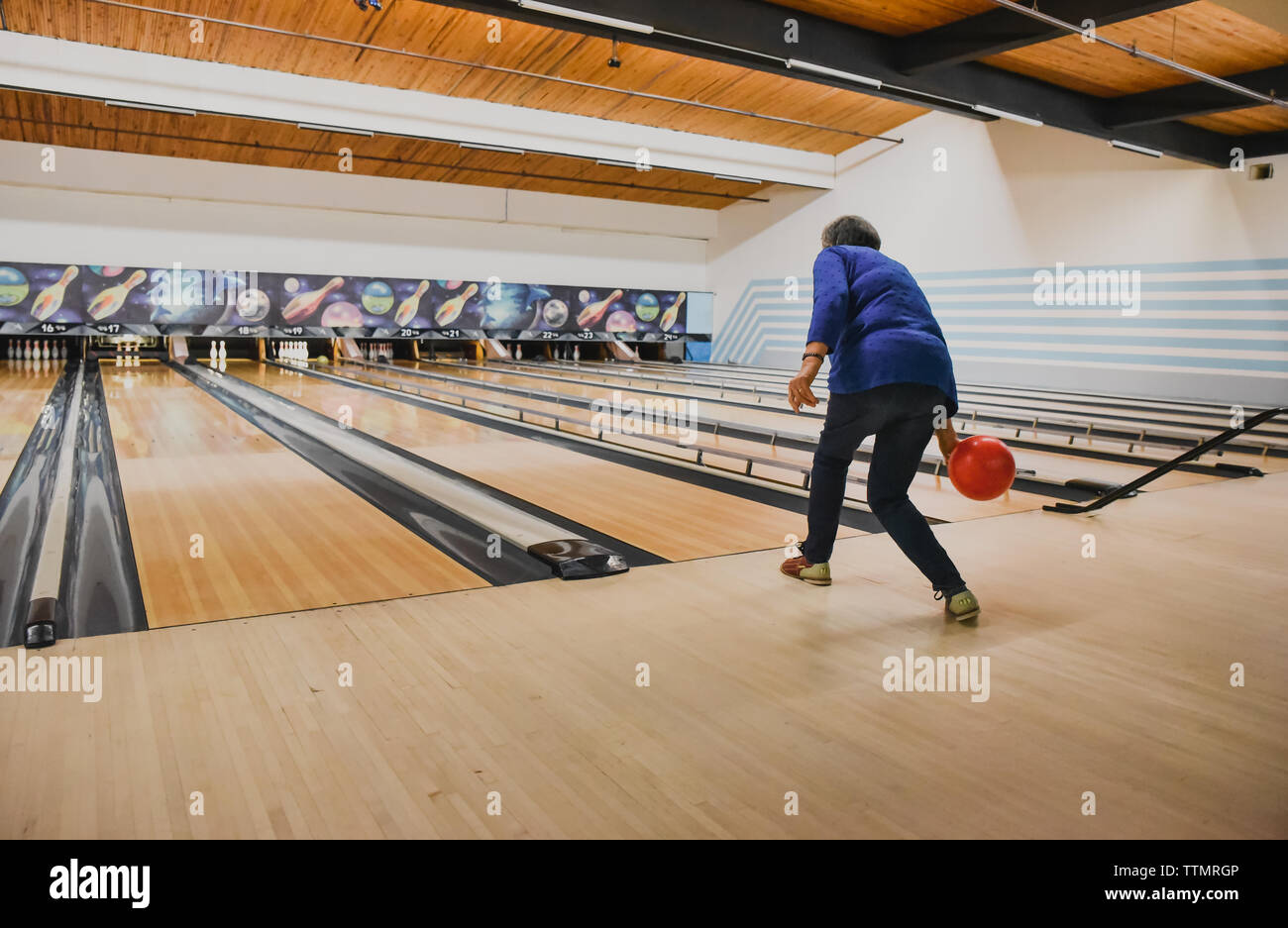 Femme plus jeter boule de bowling sur une piste de bowling. Banque D'Images