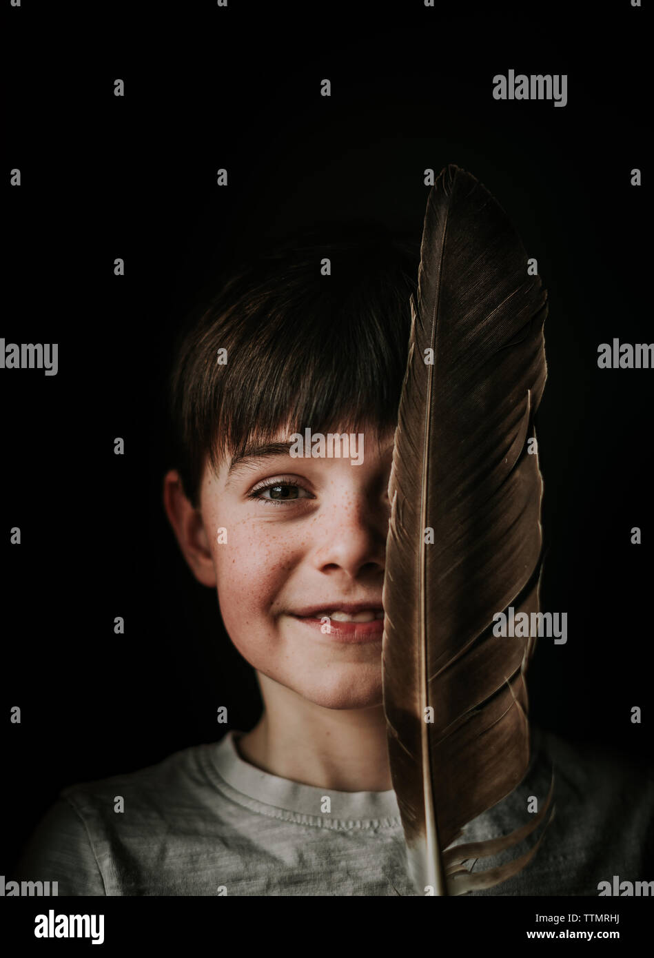 Portrait de jeune garçon tenant un grand feather plus de la moitié de son visage. Banque D'Images