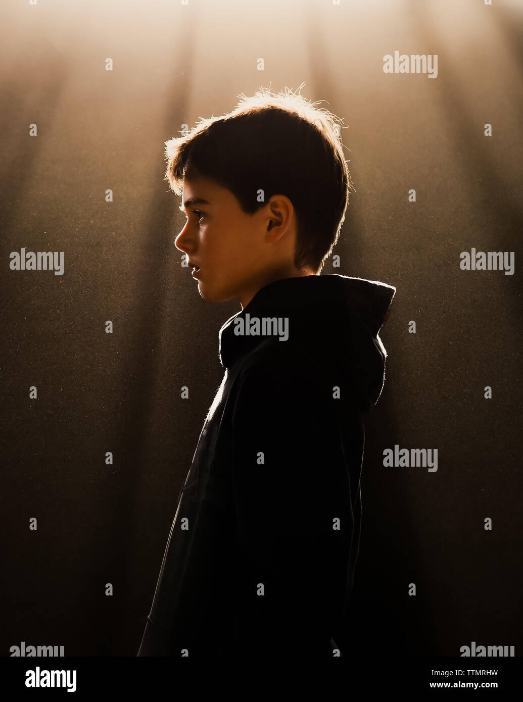 Portrait de profil de preteen boy dans ciel voilé, rétroéclairé poussiéreux. Banque D'Images