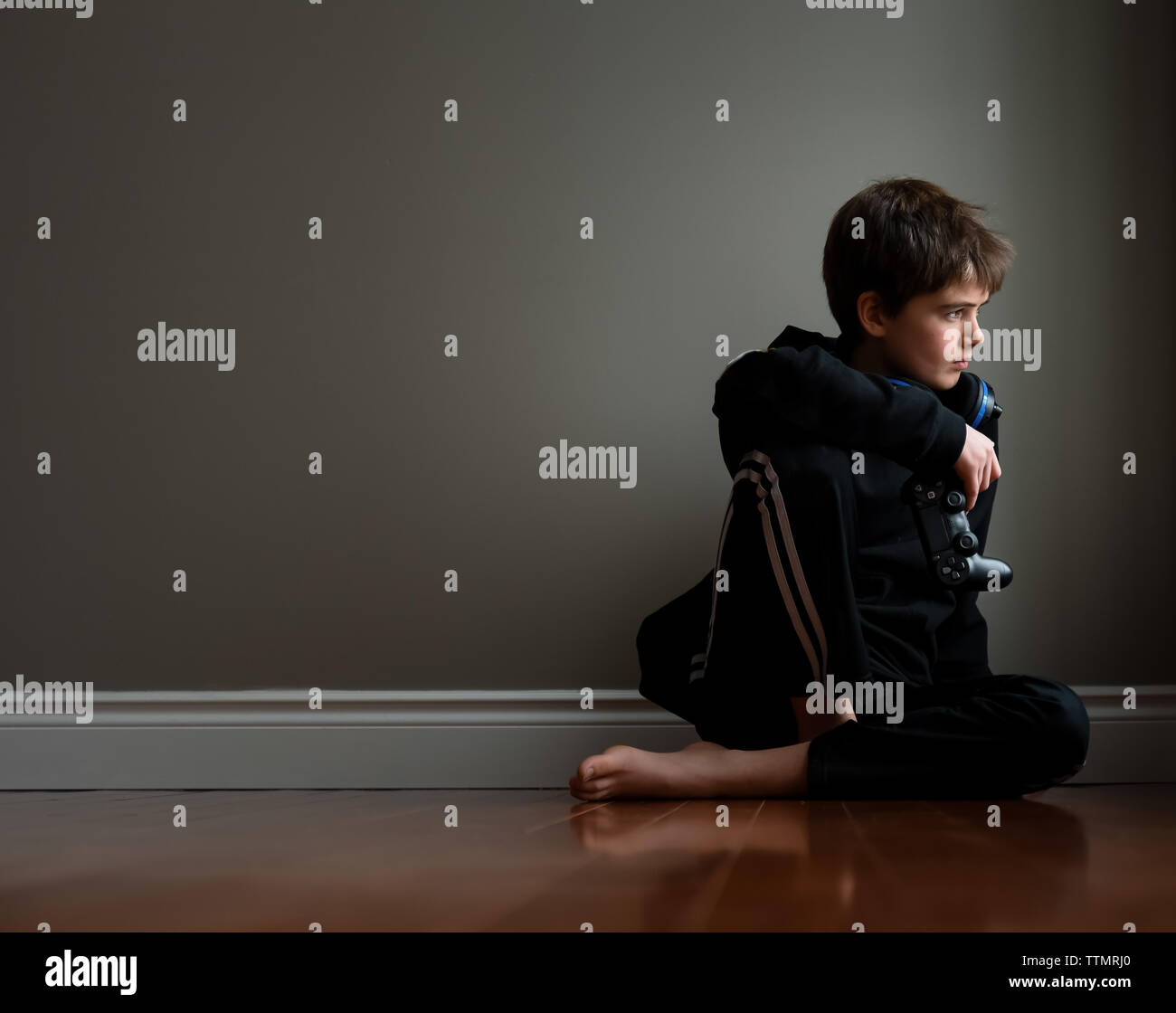 Preteen boy sitting on floor avec contrôleur de jeu vidéo dans la main. Banque D'Images