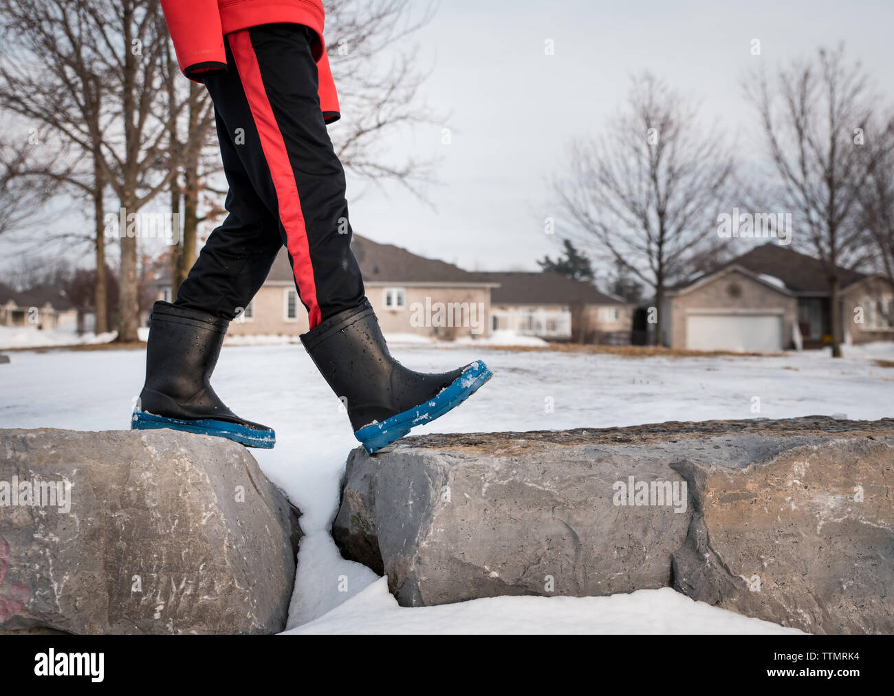 Image recadrée de la moitié inférieure du garçon marchant sur de grosses roches dans des bottes. Banque D'Images