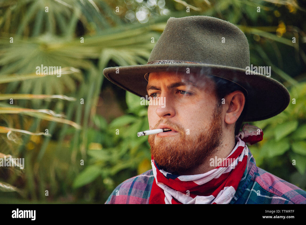 Close-up of young man wearing hat barbu et bandana en fumant cigarette Banque D'Images