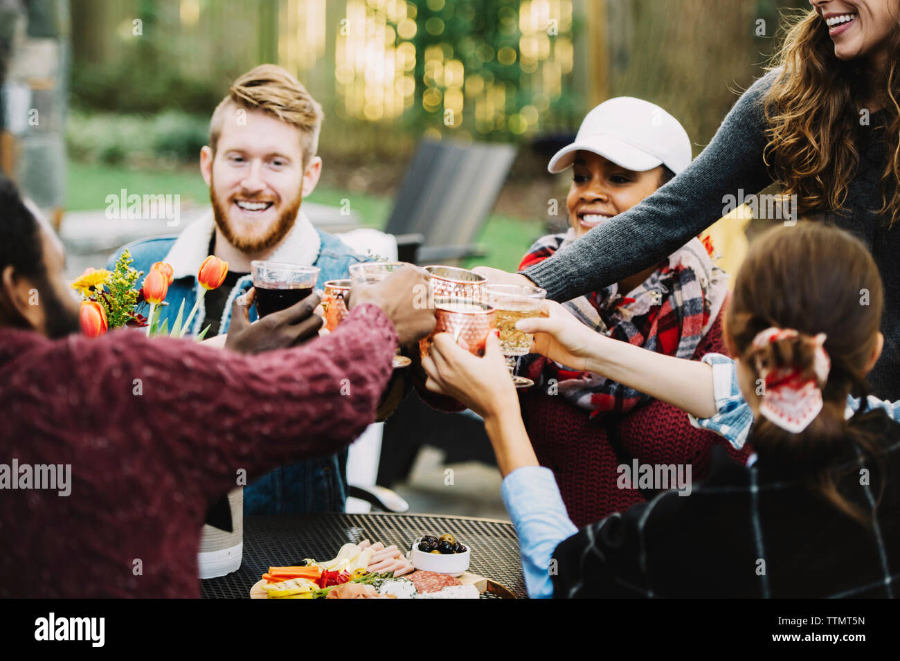 Happy friends toasting drinks while sitting in backyard Banque D'Images