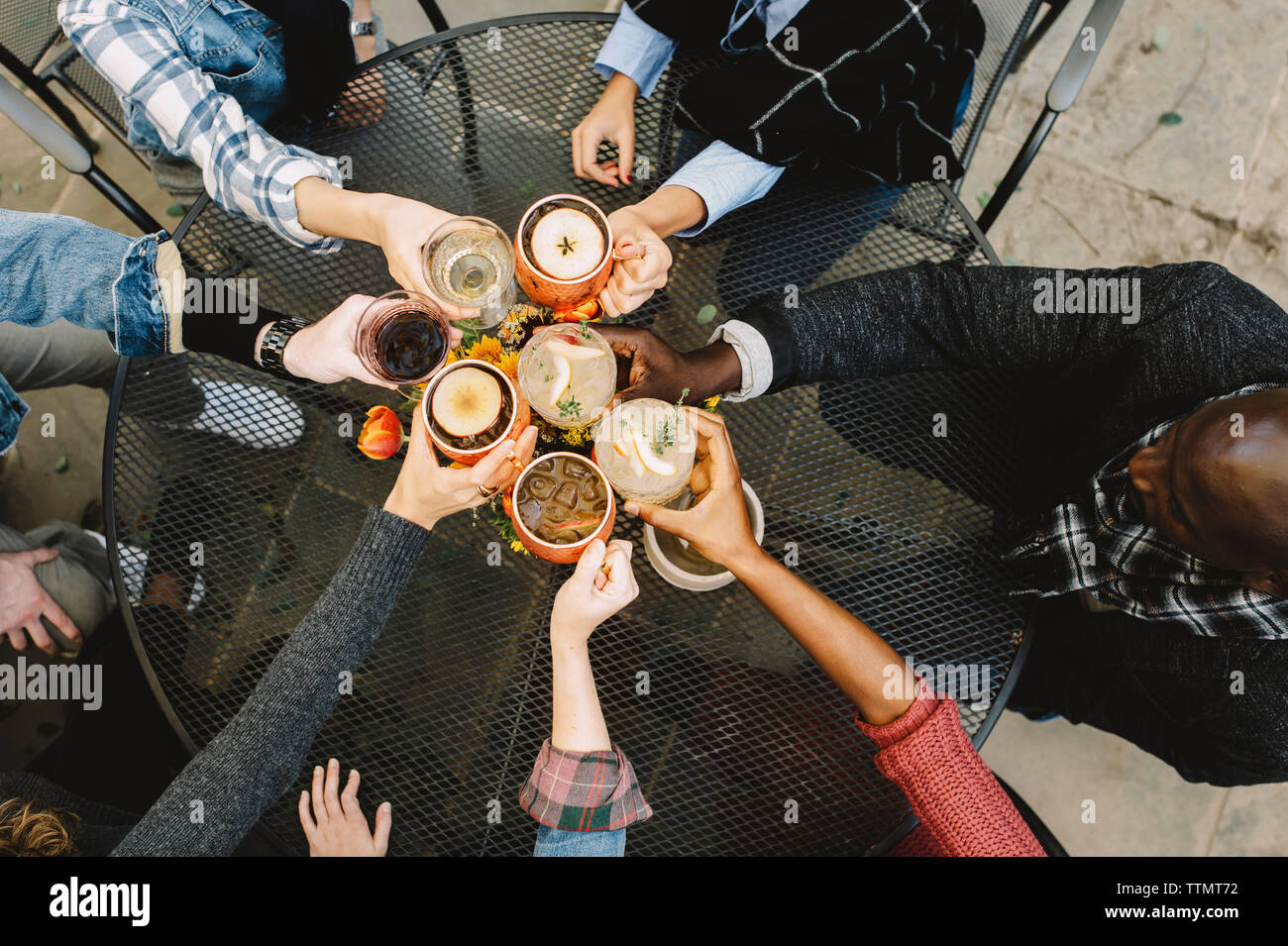 High angle view of friends toasting drinks while sitting at table in backyard Banque D'Images