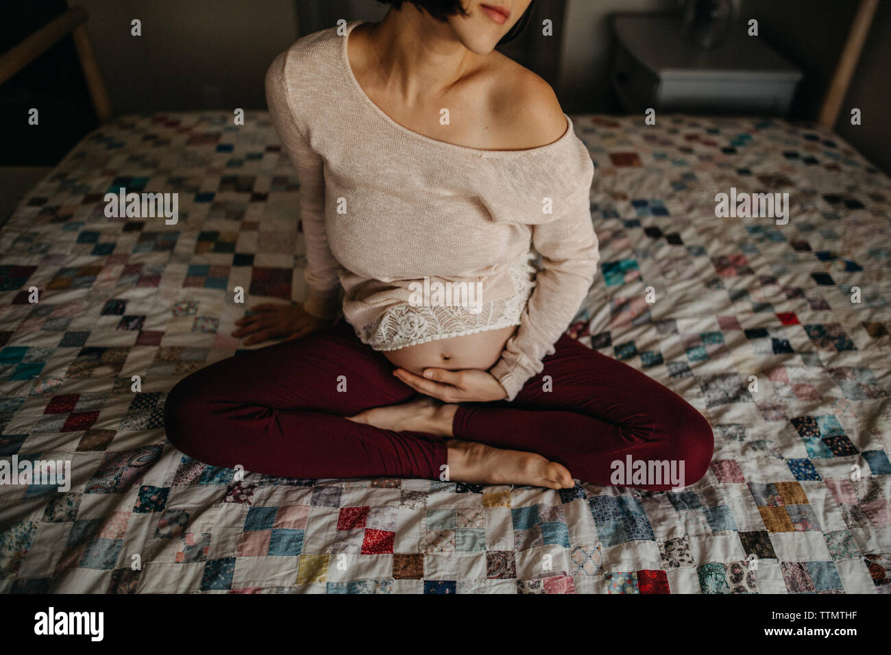 Pregnant woman holding baby bump au lit tout en souriant Banque D'Images