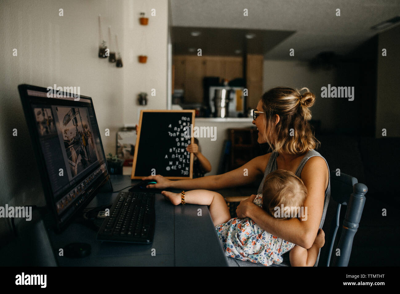 Mère au travail multitâche sur l'ordinateur et holding baby Banque D'Images