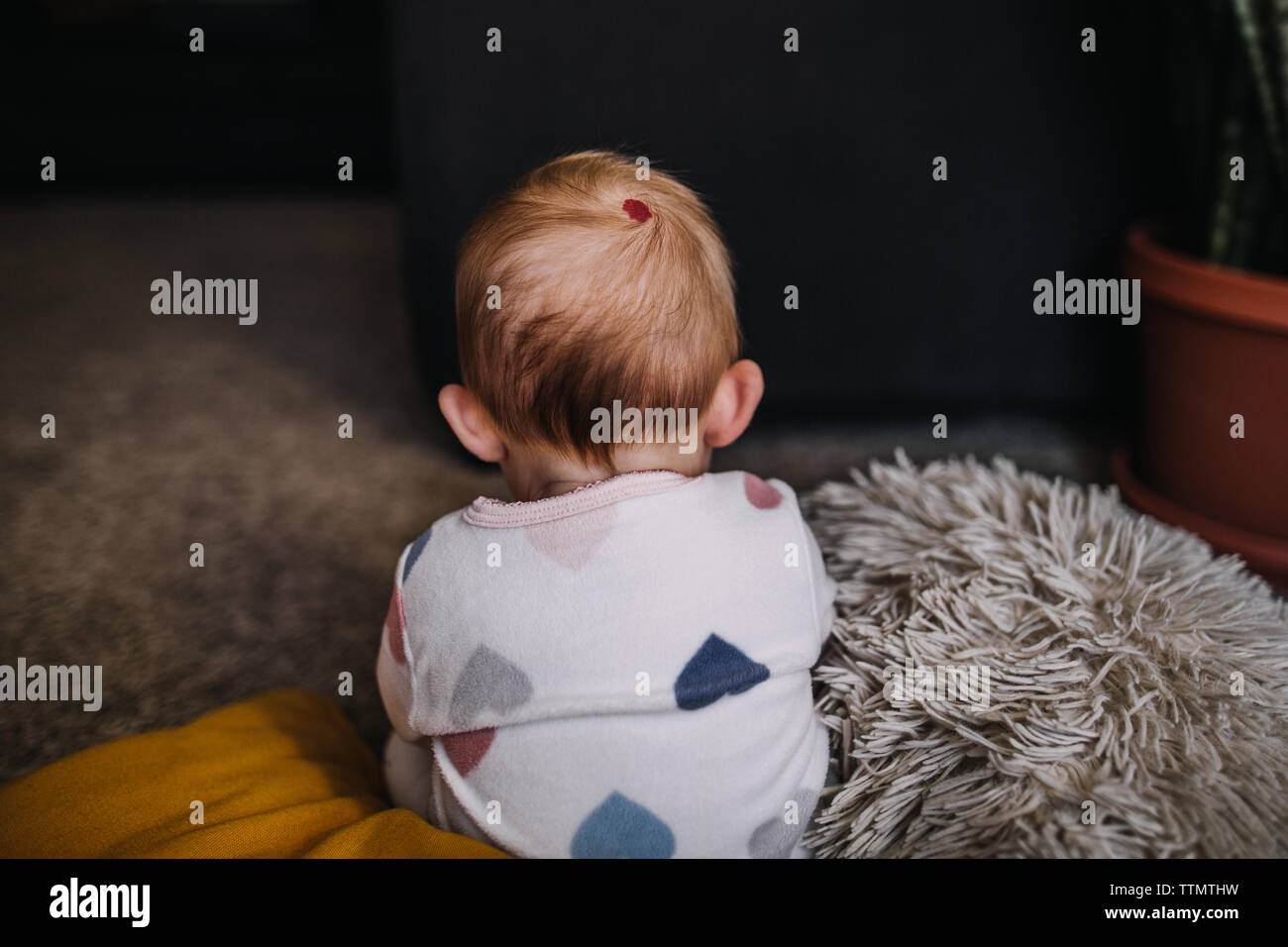 Baby sitting jusqu'à une marque de naissance rouge sur l'arrière de sa tête Banque D'Images