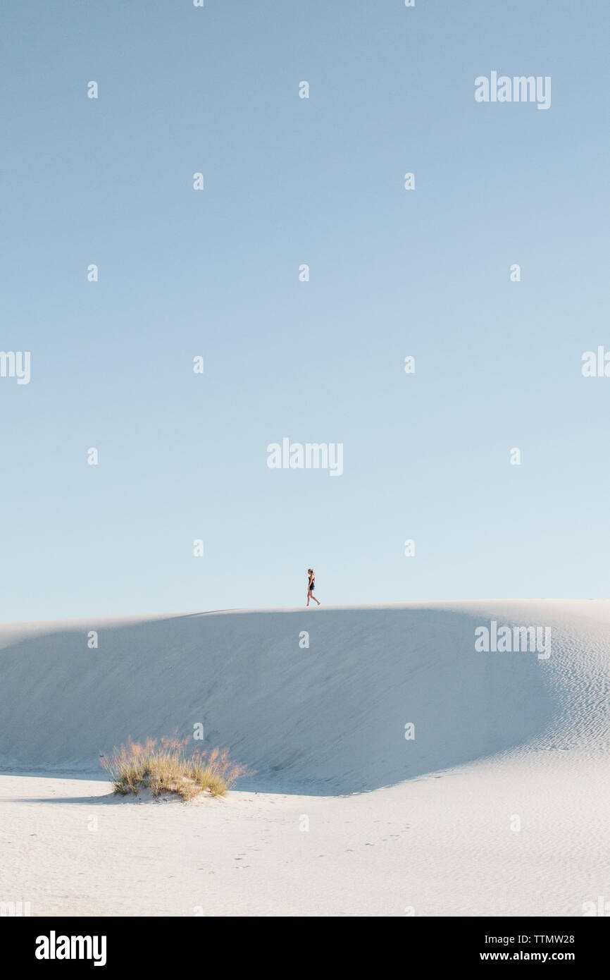 Vue éloignée sur femme marche au White Sands National Monument contre le ciel clair Banque D'Images