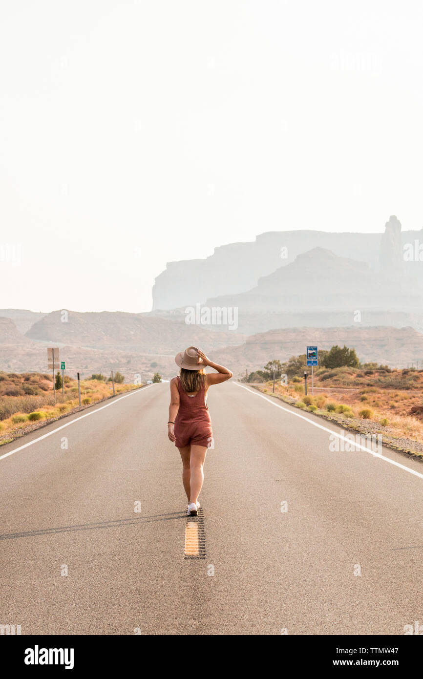 Rear view of woman wearing hat marche sur route contre ciel clair à Monument Valley Tribal Park Banque D'Images