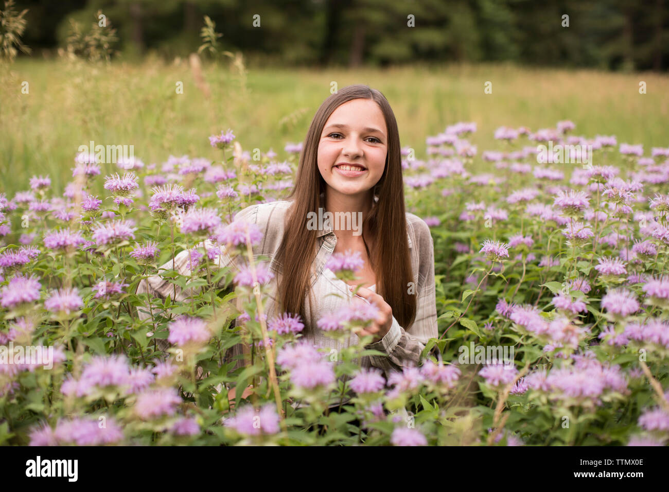 Au courant de l'appareil photo, Smiling, fille de l'adolescence se trouve dans un champ de fleurs violettes Banque D'Images