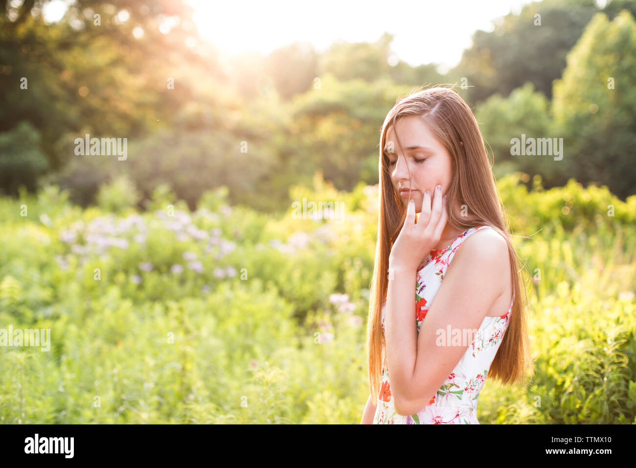 Teenage Girl avec les yeux fermés est en champ dans la lumière du soleil Banque D'Images