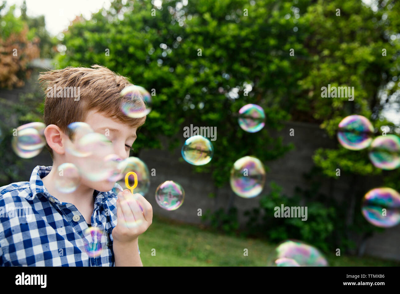 Boy blowing bubbles in yard Banque D'Images