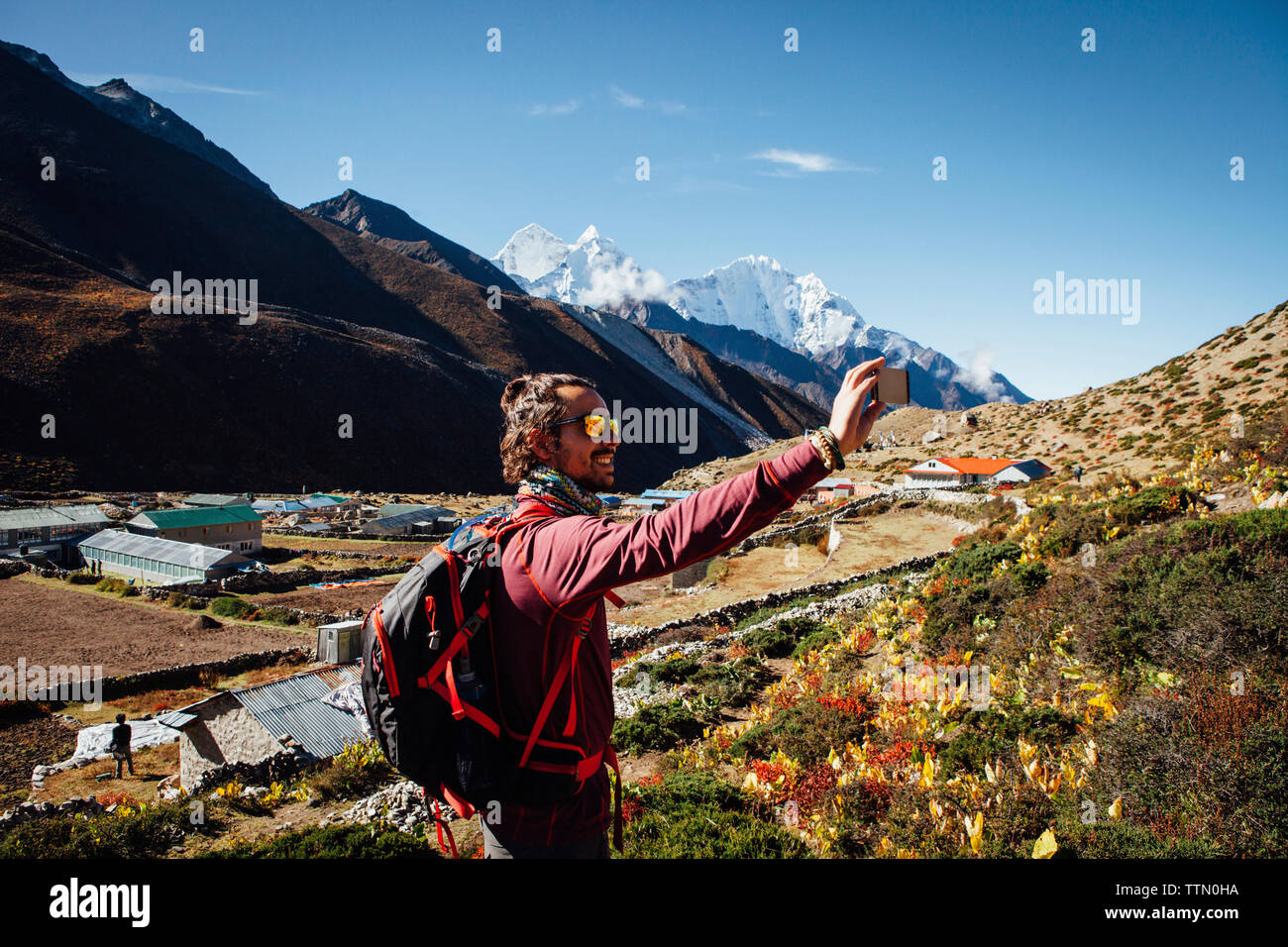 Male hiker selfies en tenant en position debout contre le ciel bleu de montagne au parc national de Sagarmatha Banque D'Images