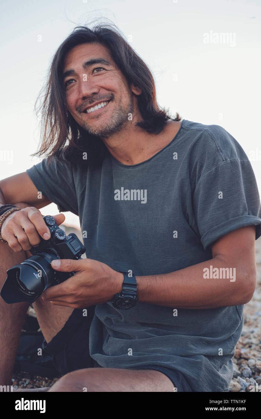 Personne souriante à l'appareil photo sur la plage pendant l'utilisation d'appareil photo Banque D'Images