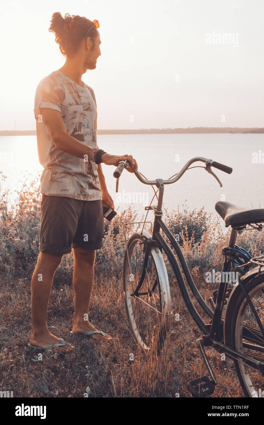 Homme à côté de son vélo piscine en été à le coucher du soleil Banque D'Images