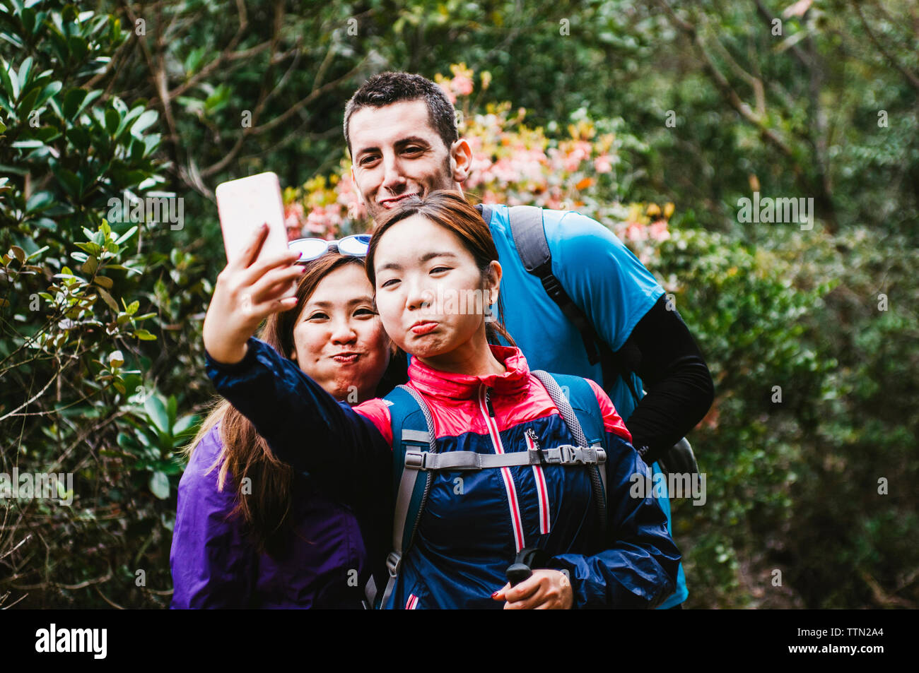 Happy friends en tenant debout selfies en forêt Banque D'Images