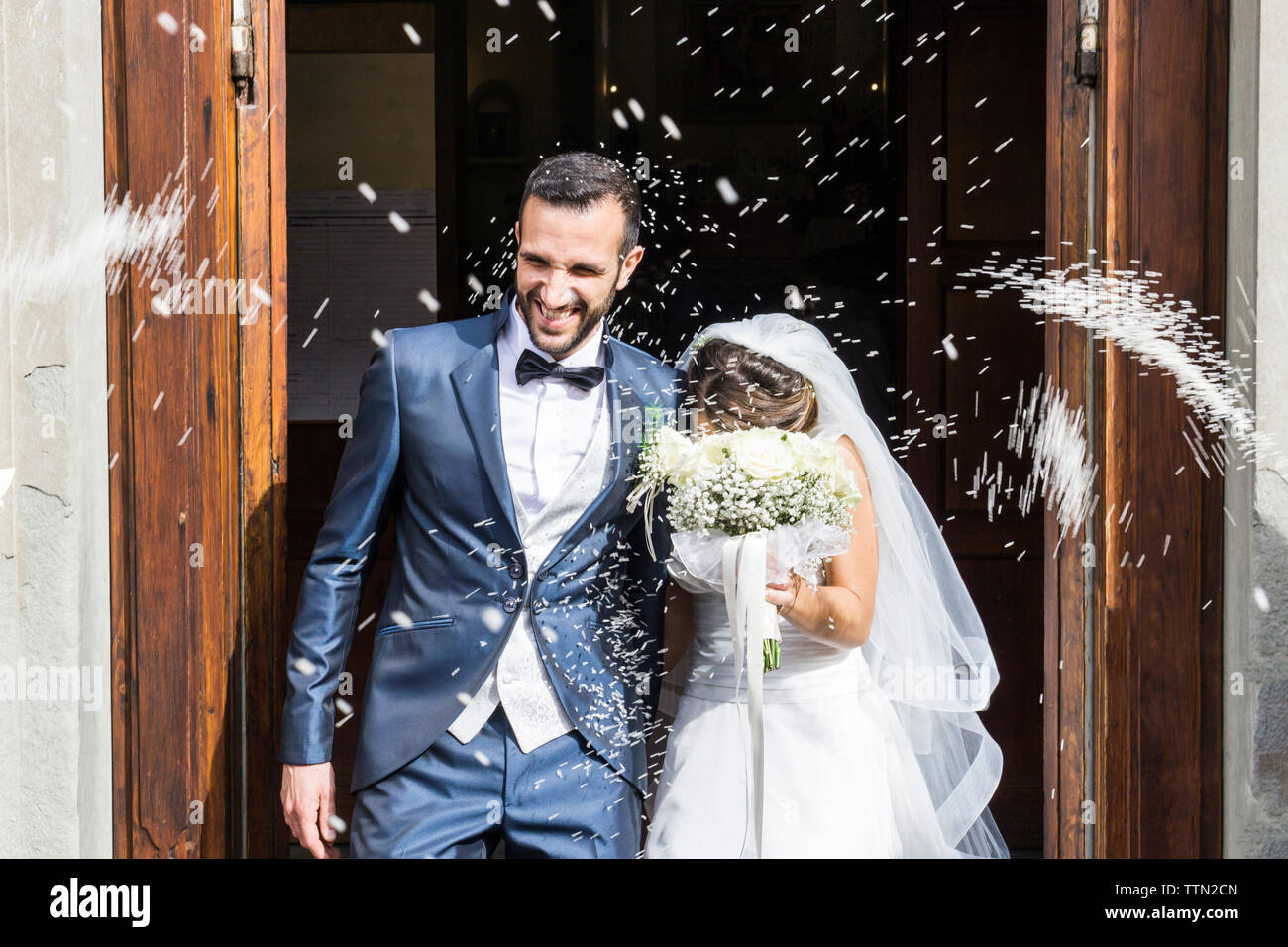 Jeter des confettis sur happy senior couple debout à l'entrée de l'église Banque D'Images