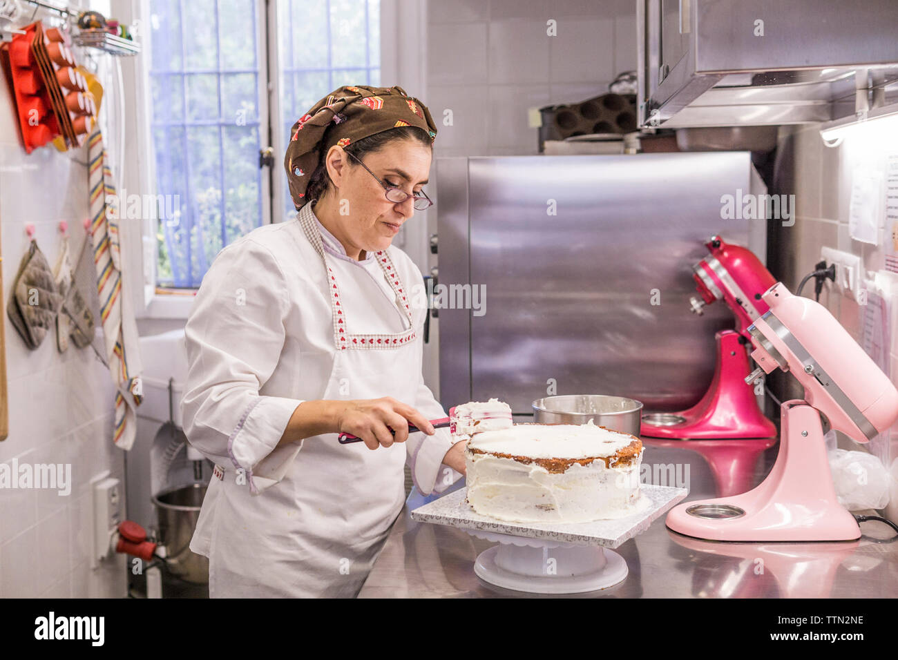 Baker femelle faisant gâteau sur compteur de cuisine in laboratory Banque D'Images