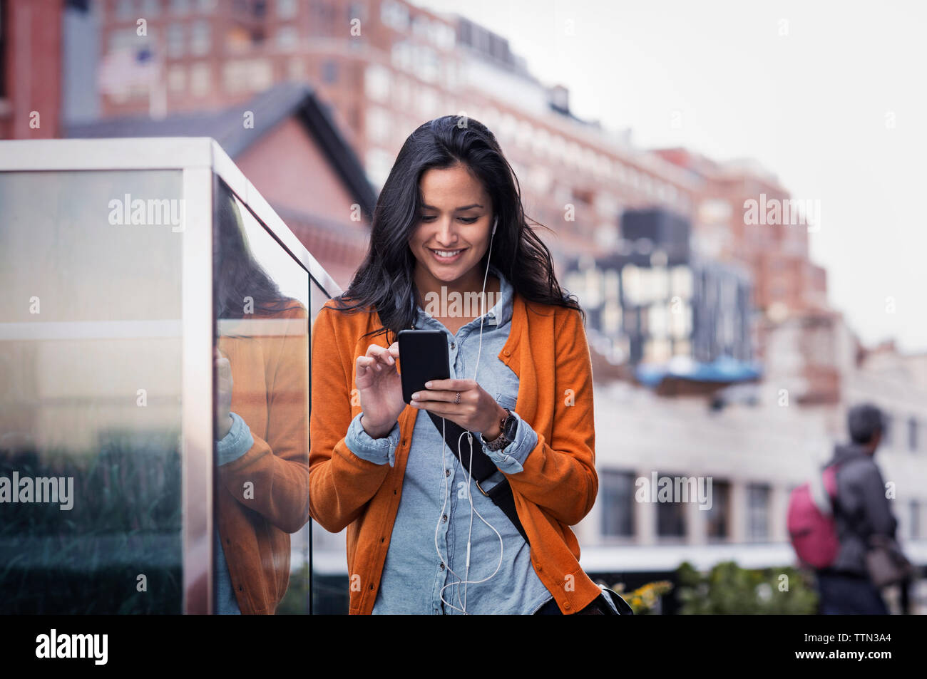 Young woman texting on sidewalk Banque D'Images