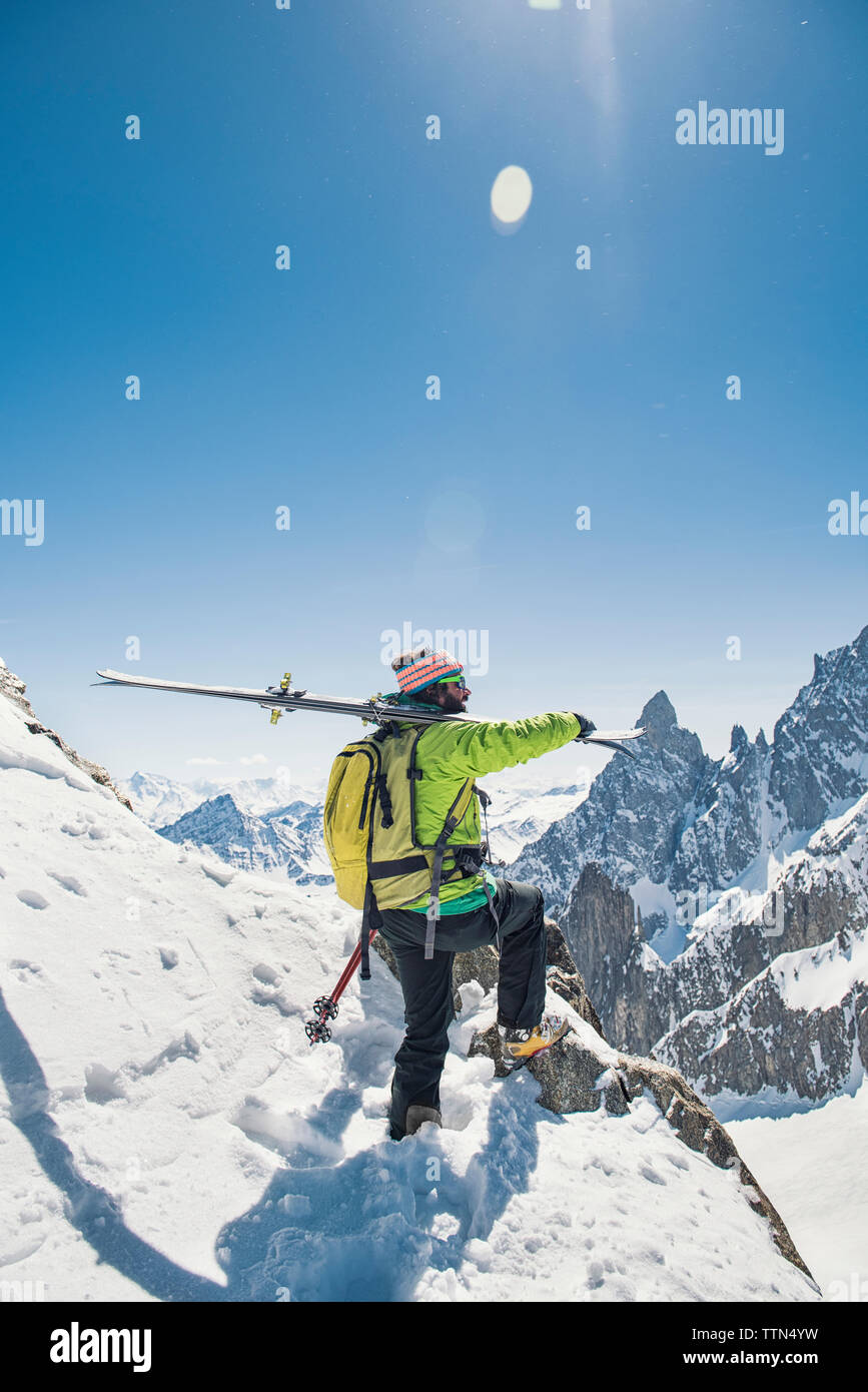 Vue latérale du randonneur avec skis debout sur la montagne couverte de neige contre ciel bleu clair au cours de journée ensoleillée Banque D'Images