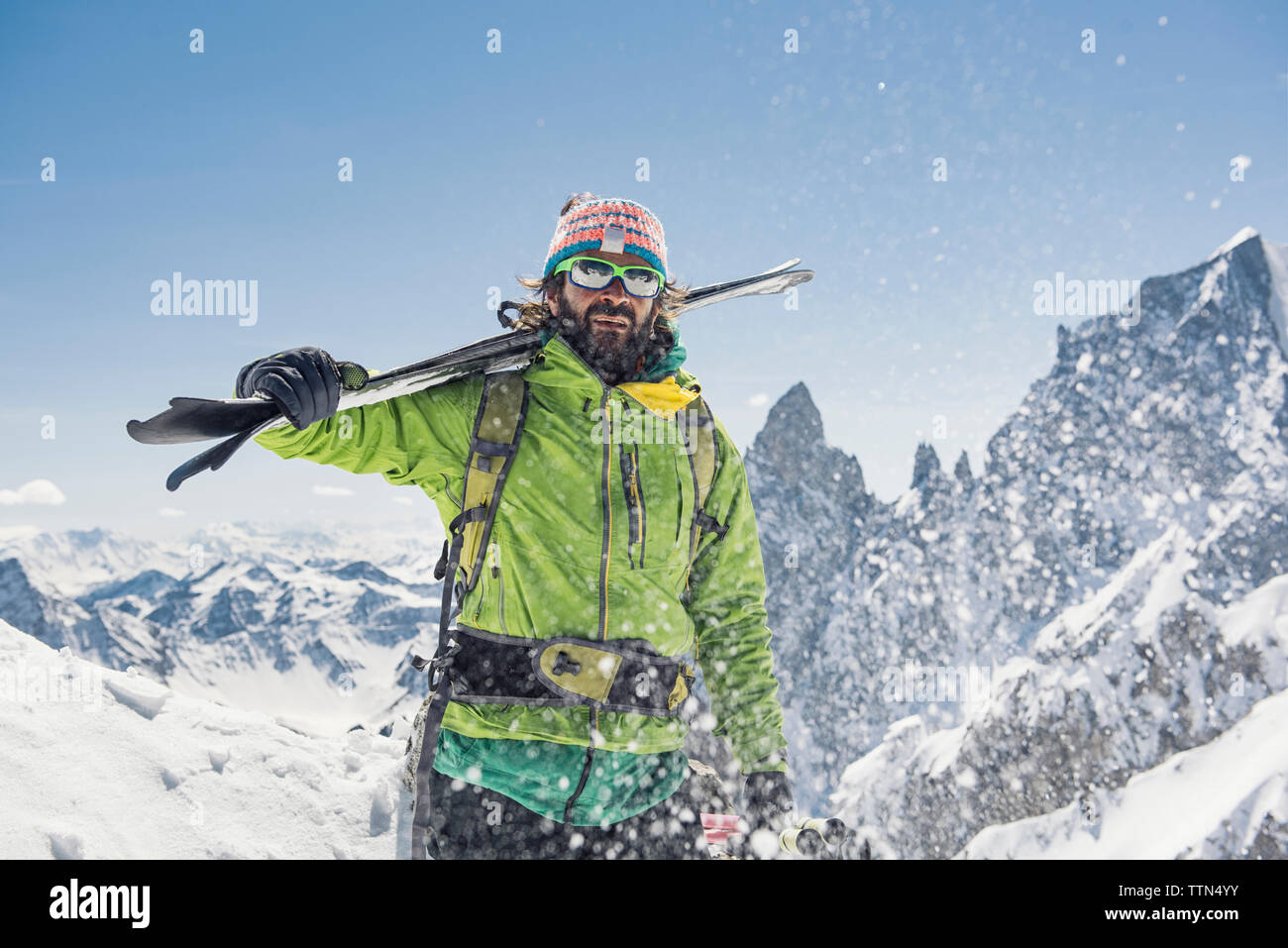 Randonneur avec skis debout sur la montagne couverte de neige contre un ciel clair au cours de journée ensoleillée Banque D'Images