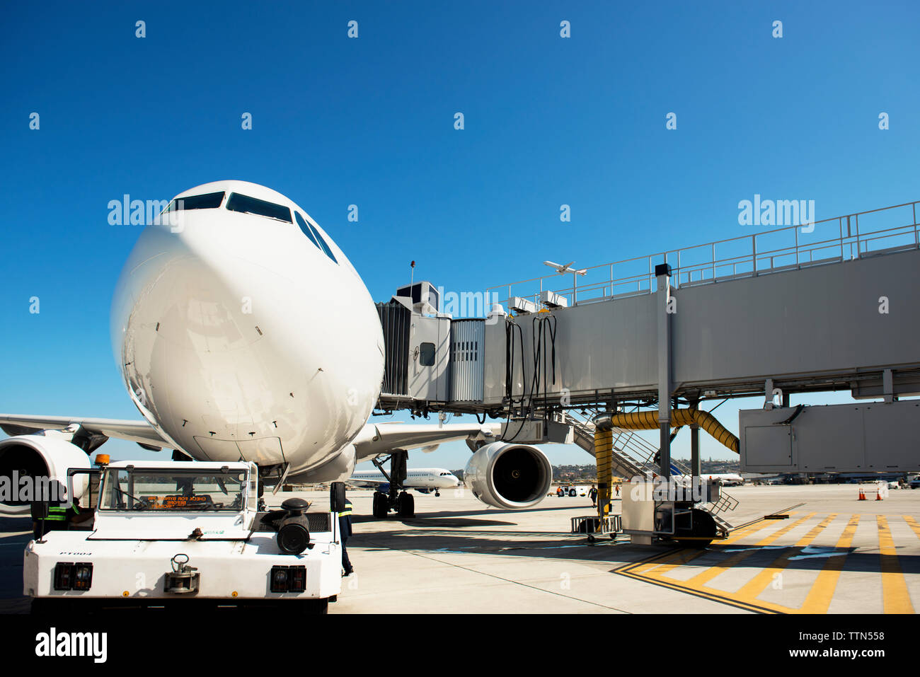 Pont d'embarquement des passagers et de l'avion sur la piste contre ciel bleu clair Banque D'Images