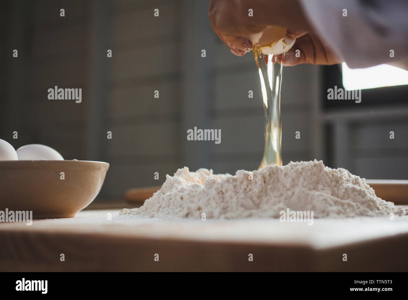 Portrait de femme casser l'oeuf dans la farine sur le tableau Banque D'Images