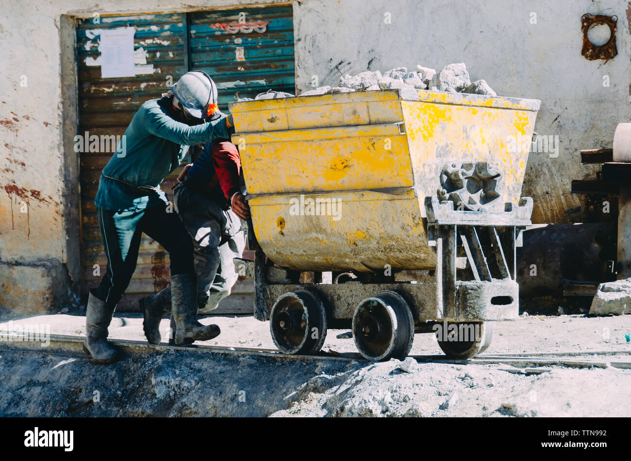 ouvriers poussant le conteneur sur le chantier de construction Banque D'Images