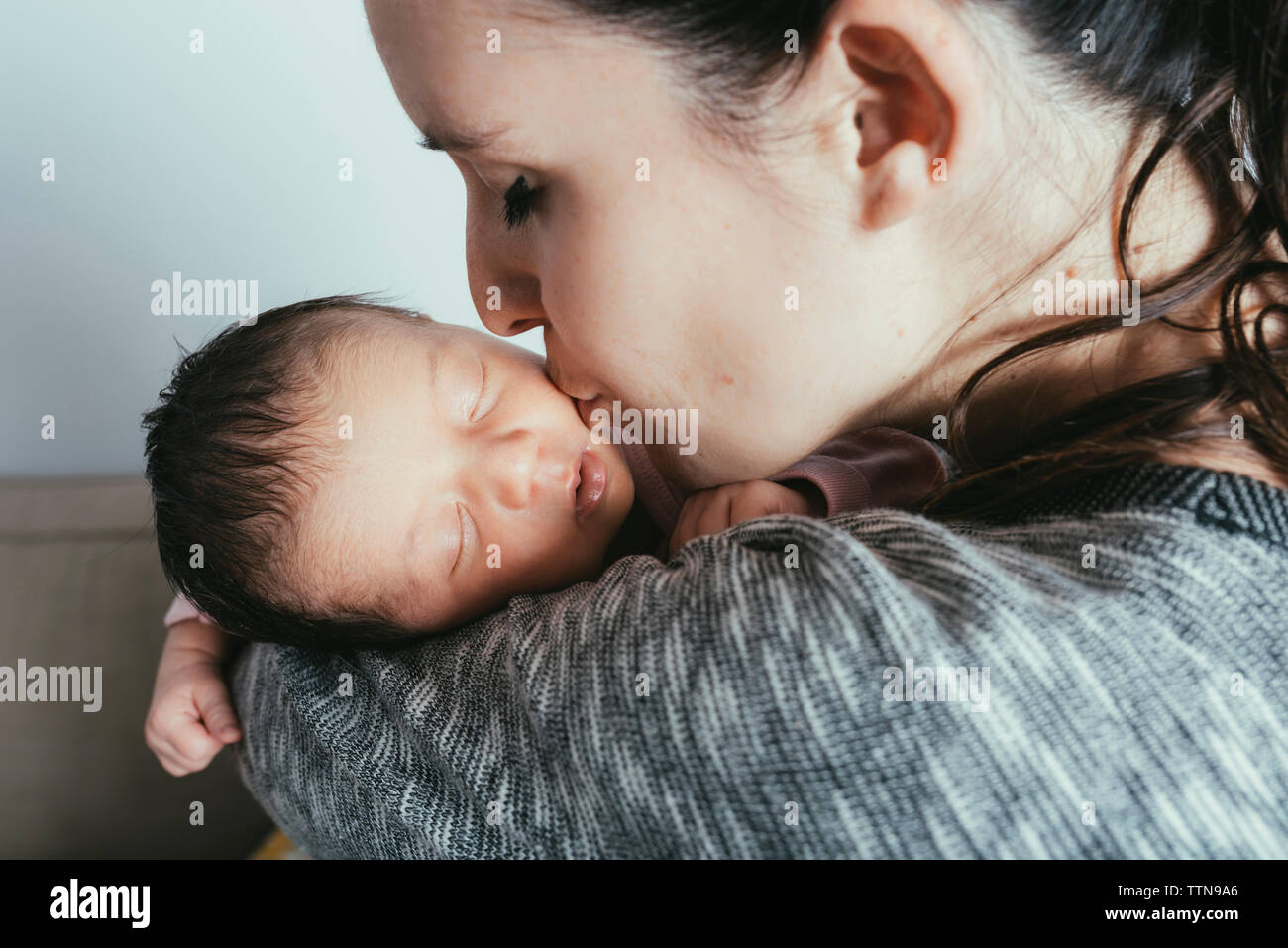 Close-up of woman kissing baby girl at home Banque D'Images