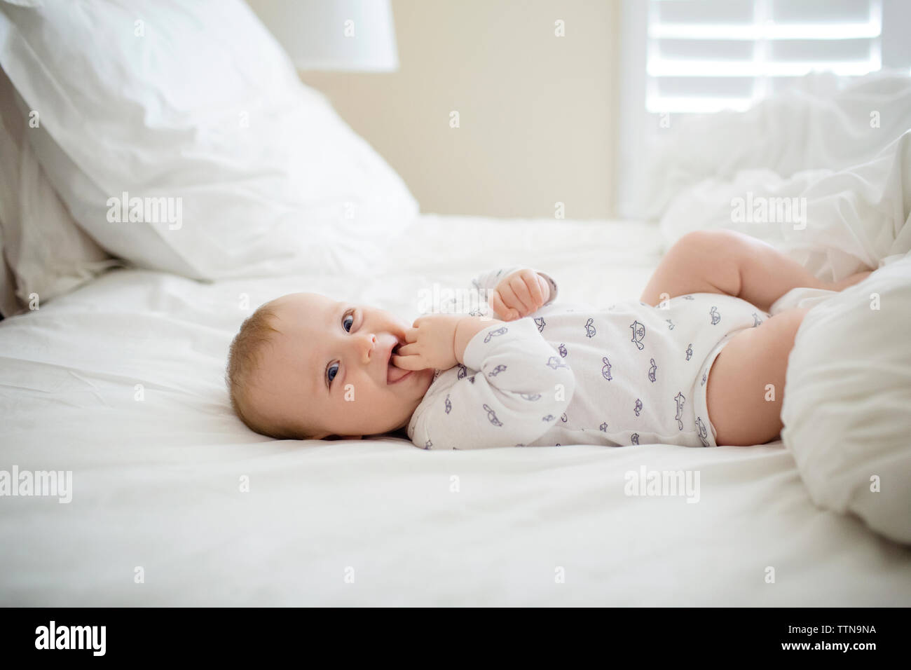 Cheerful baby boy lying on bed at home Banque D'Images