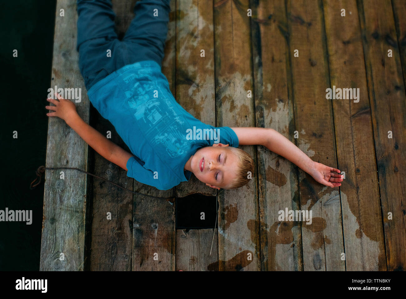 Vue de dessus de garçon couché sur la jetée en bois Banque D'Images