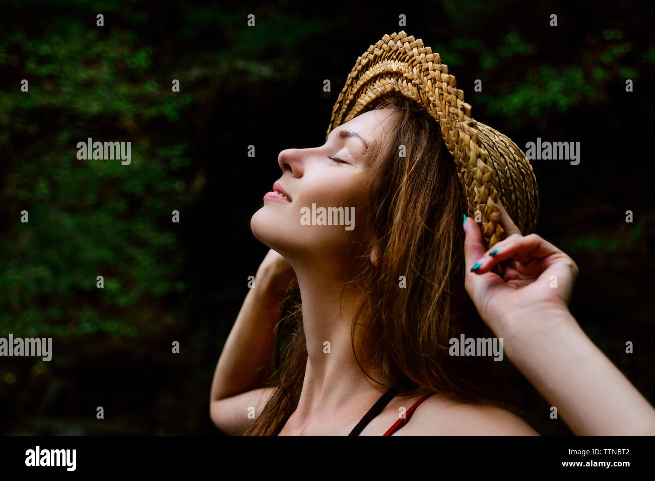 Close-up of smiling woman wearing hat debout contre des arbres en forêt Banque D'Images