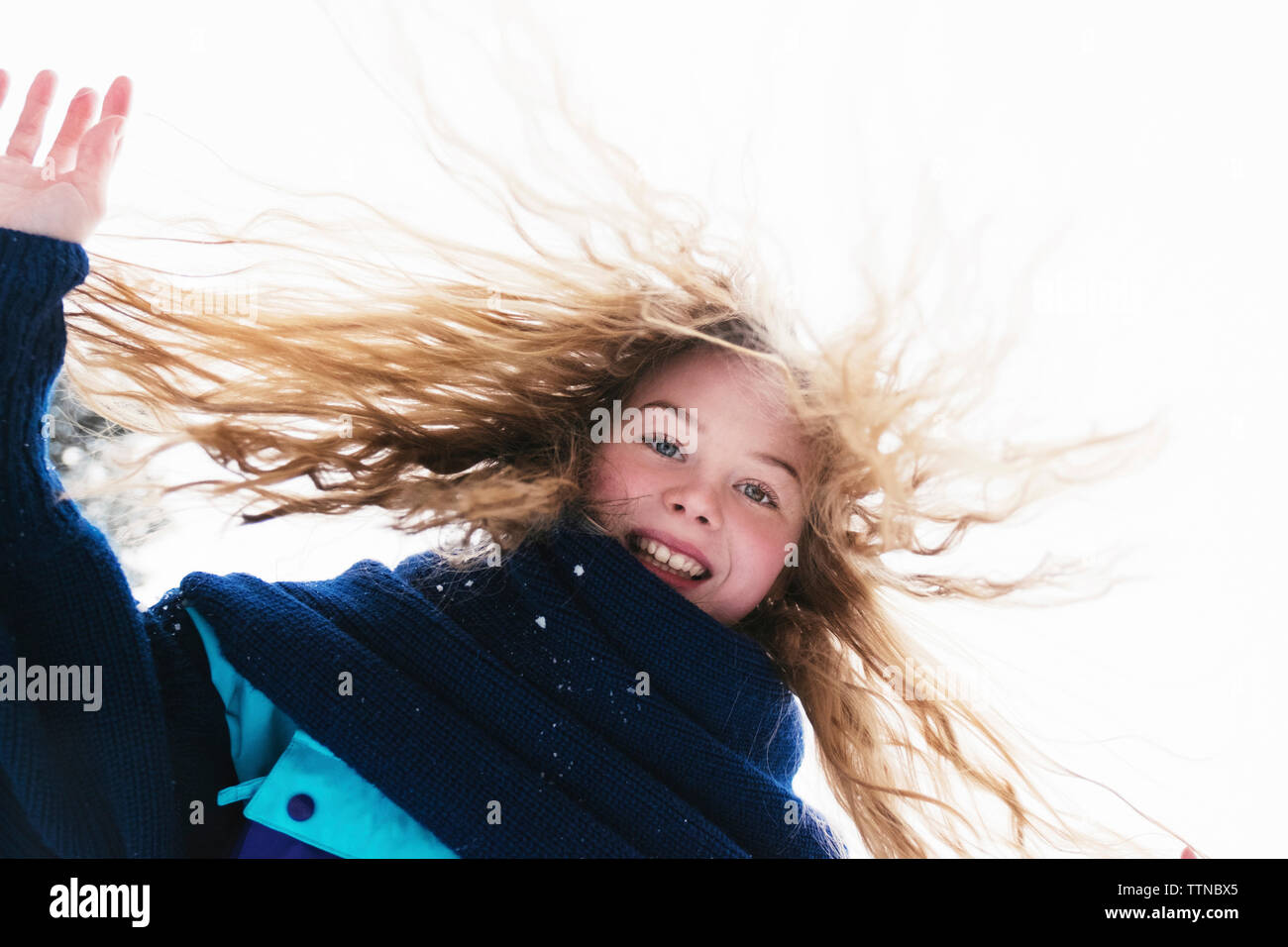 Low angle portrait de femme heureuse avec des cheveux blonds debout contre un ciel clair au cours de l'hiver Banque D'Images