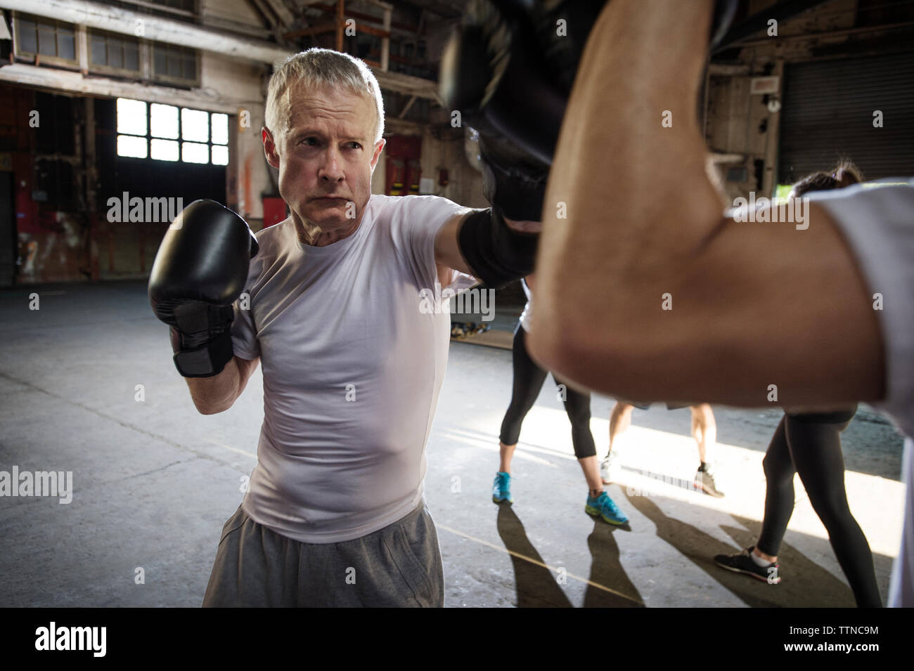 Déterminé senior male boxer pratiquant avec ami dans un club de santé Banque D'Images